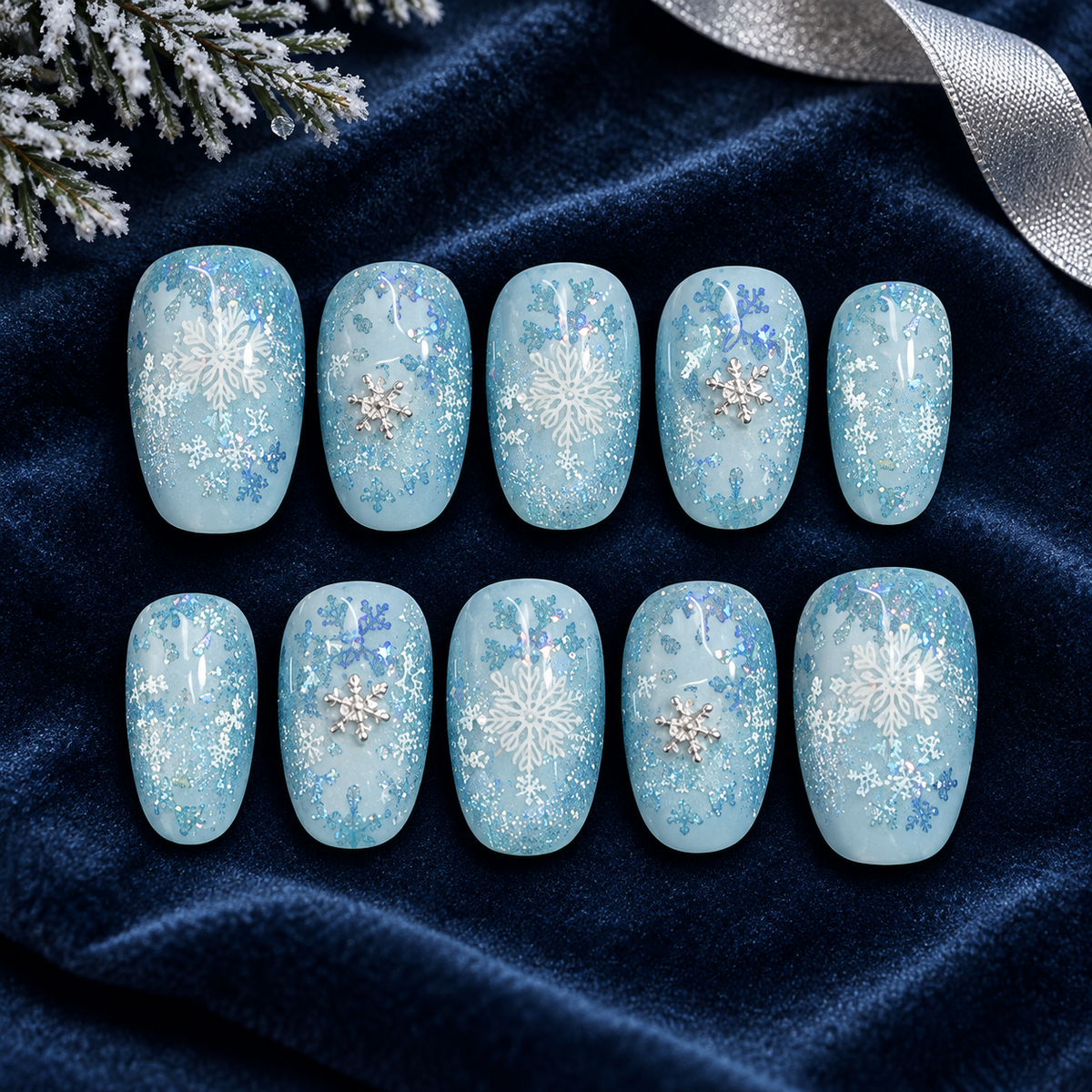 The Cold Looks Good on Me — ten icy blue press-on nails with white and silver snowflakes, styled on midnight-blue velvet